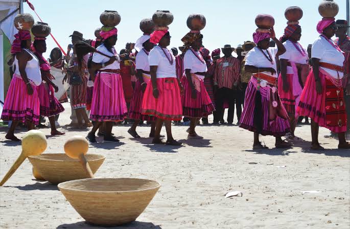Owambo women in traditional dress beside clay pots