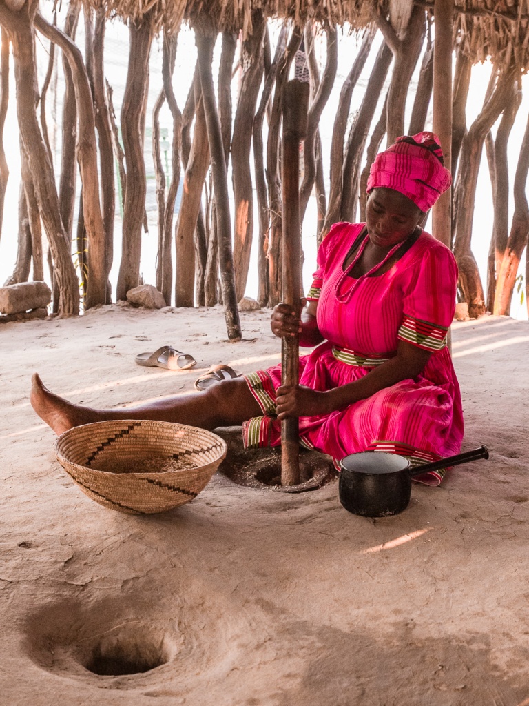 An Owambo host preparing food inside a traditional homestead
